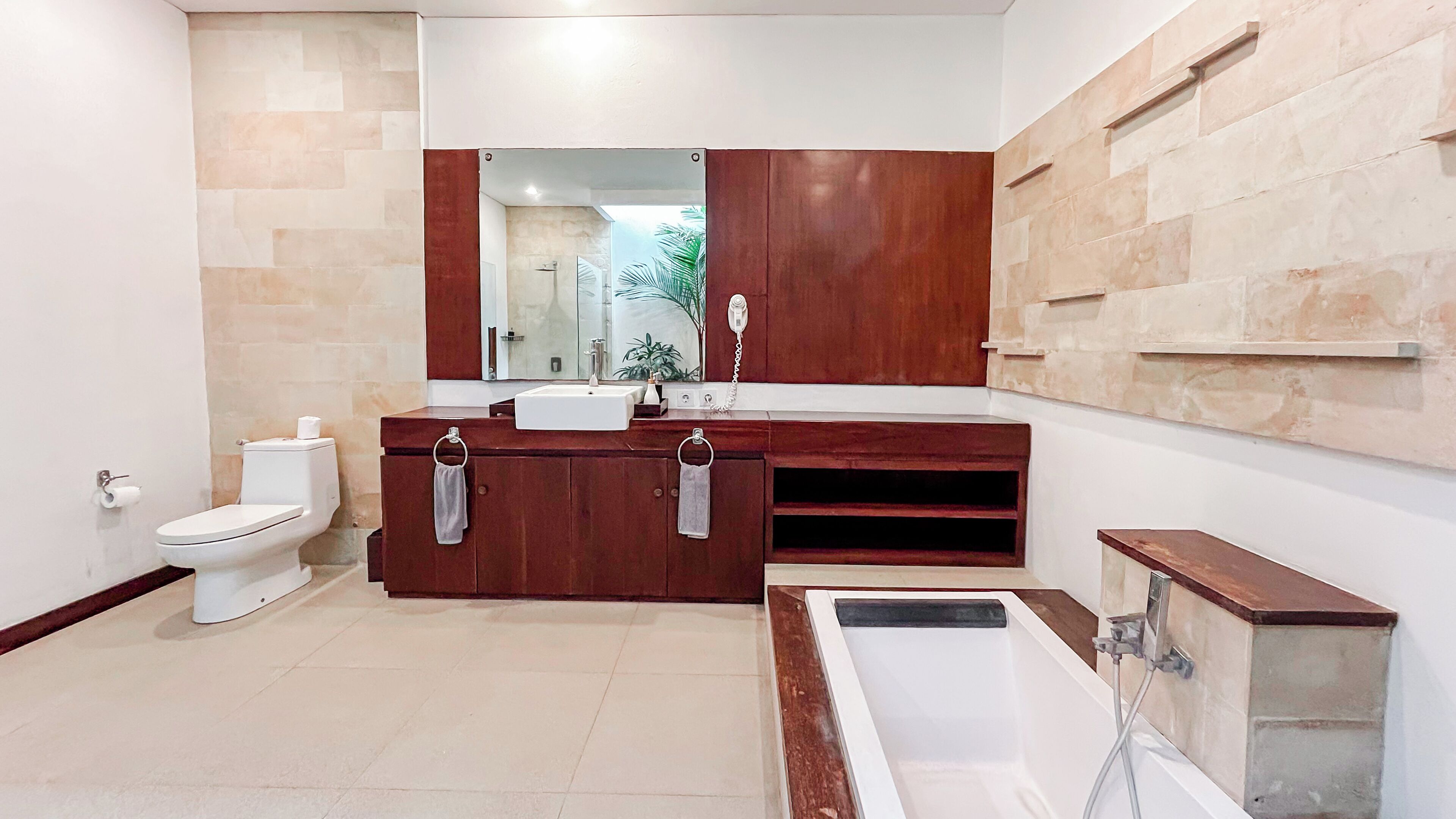 A modern bathroom with a toilet, sink, vanity, mirror, and bathtub.