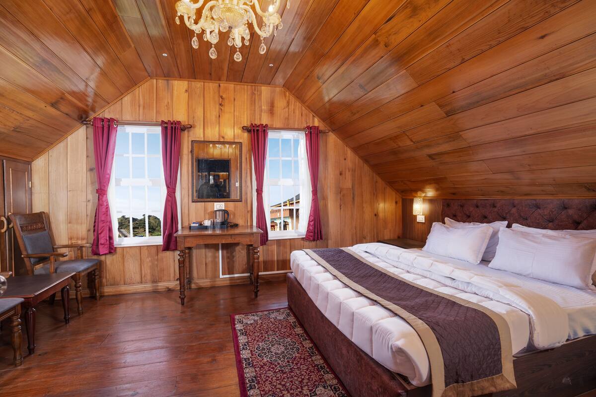 Une chambre aux murs lambrissés, avec un grand lit, un bureau et une chaise.