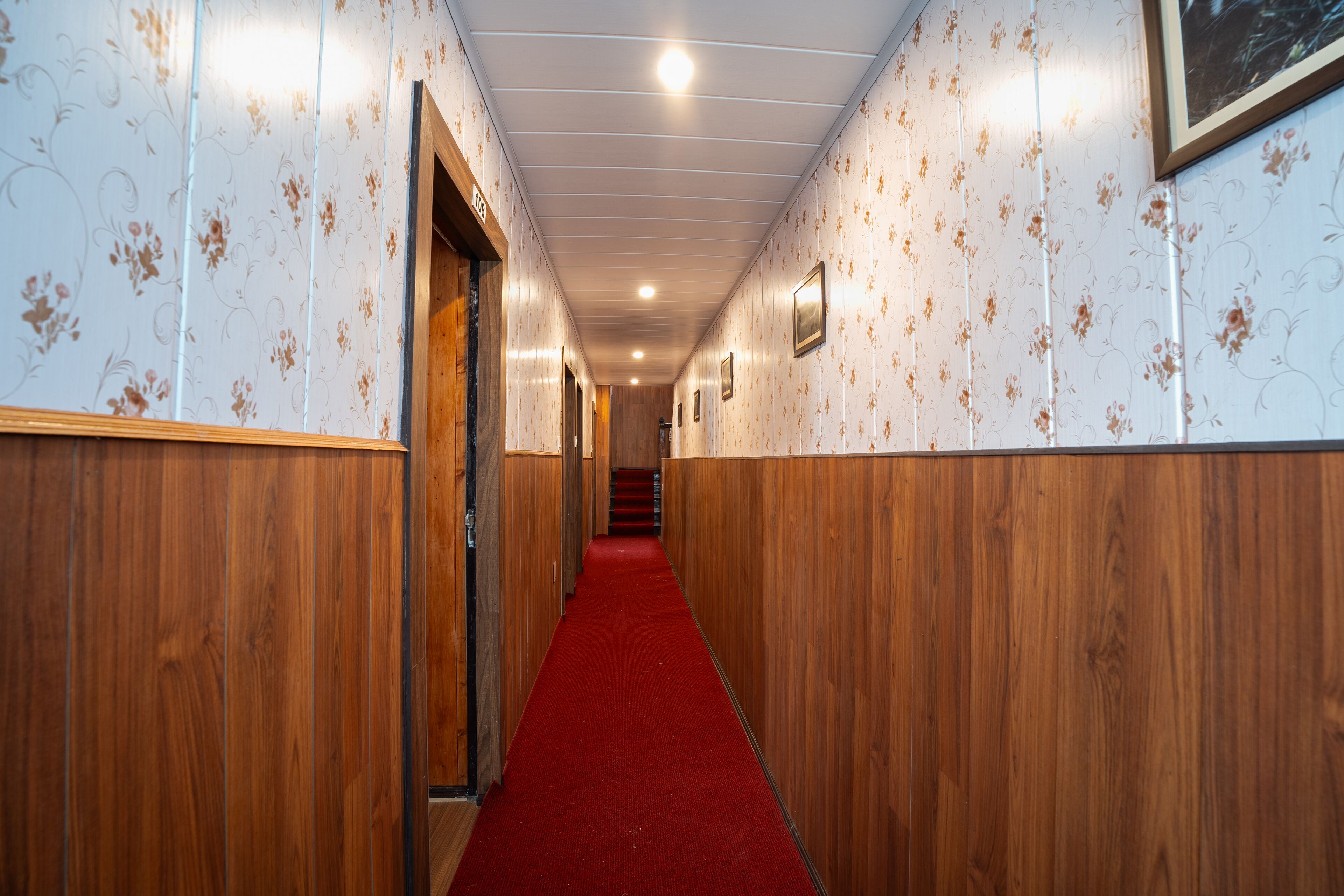 A hallway with wooden paneling, a red carpet, and floral wallpaper.