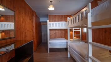 A room with bunk beds, wooden walls, a mirror, and a ceiling light.