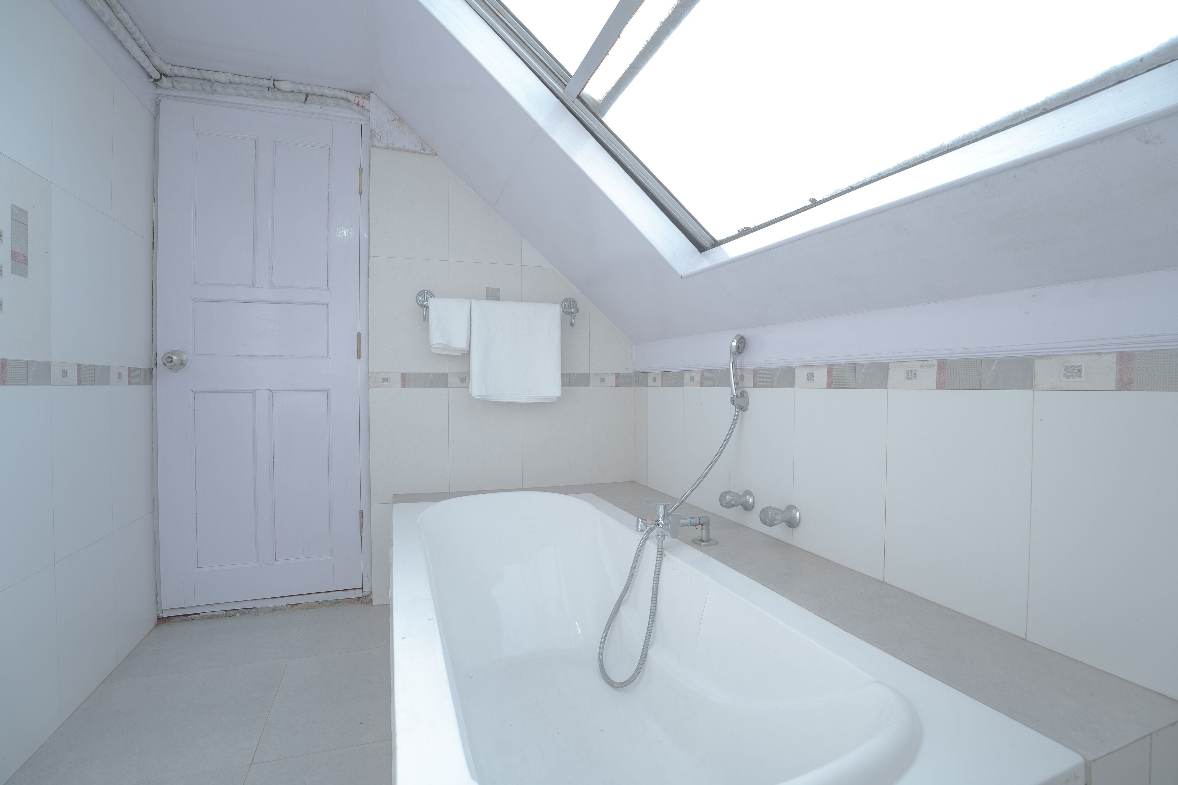 A modern bathroom with a skylight, a bathtub, and a shower.