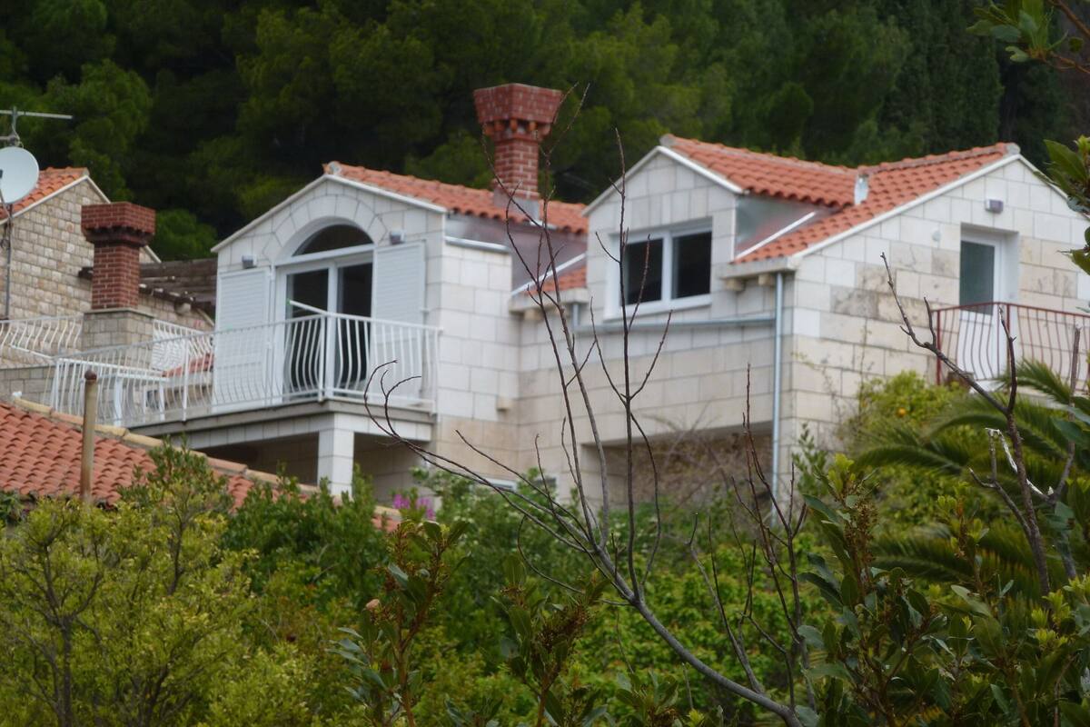A residential building with a balcony, a chimney, and a tiled roof.