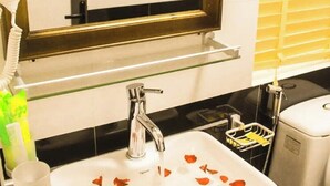 A bathroom with a white sink, a mirror, and a glass shelf above it.