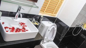 A bathroom with a white sink, a toilet, and a glass shelf above the sink.