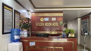 A reception desk at the Golden Moon Hotel with a wooden finish, a water dispenser, and a fan.