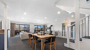 Un intérieur moderne comprenant un coin repas, un canapé et un escalier.
