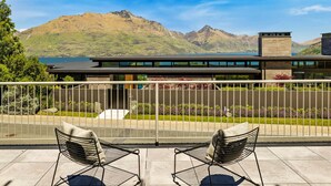 Un balcon avec deux chaises, une vue sur les montagnes et un bâtiment à l’architecture moderne.