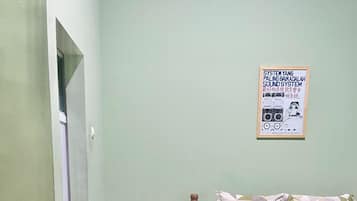 A bedroom with a bed, a nightstand, a poster on the wall, and a door leading to another room.