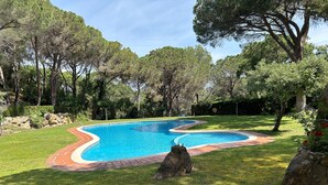 A swimming pool with a curved edge, surrounded by a well-maintained lawn and trees. - Preciosa Casa, con Enorme Piscina en Zona Tranquila y Familiar (Sant Feliu de Guixols)