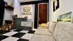 Zona reception di un hotel con banco accettazione, una poltrona e un quadro appeso al muro.