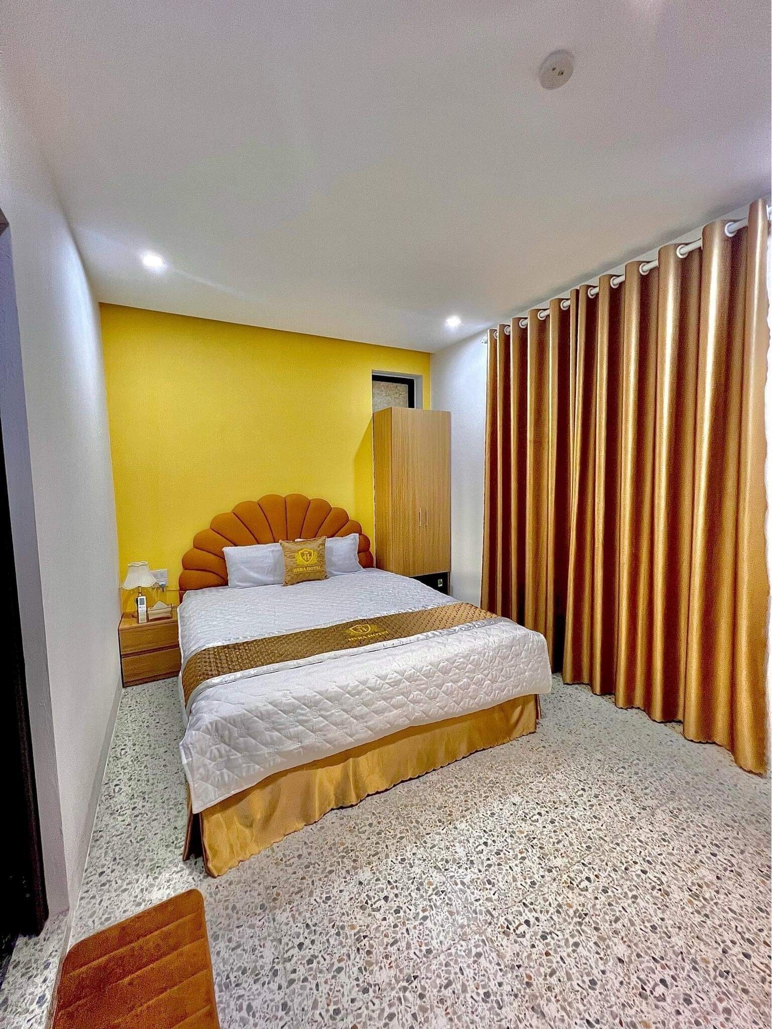 Ein Hotelzimmer mit Bett, Nachttisch, Kleiderschrank und Vorhang.