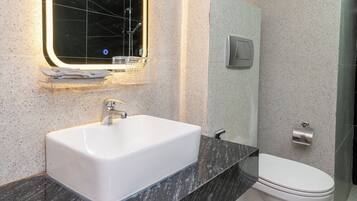 Un baño con lavamanos blanco, un espejo y un inodoro.
