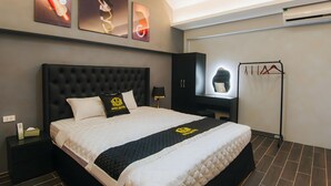 Una camera d'albergo moderna con un letto grande, una testata nera e un comodino nero. Sopra il letto, tre opere d'arte appese al muro.