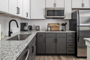 A modern kitchen with a granite countertop, stainless steel appliances, and dark cabinetry.