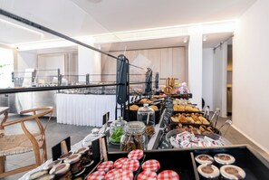 A buffet setup with various food items and a seating area with a chair. - Rochari  (Mykonos)