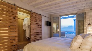 Un dormitorio con una cama grande, paredes de paneles de madera, una puerta corredera, un televisor y un balcón con vistas.