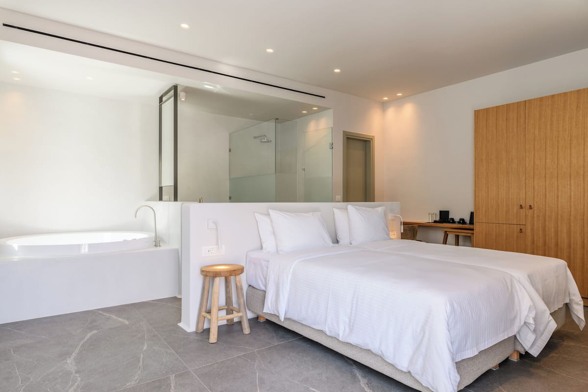 A modern bedroom with a large bed, a built-in bathtub, and a wooden wardrobe.