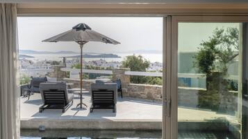 Una habitación moderna con puerta de vidrio que da a una zona de piscina, con tumbonas y una sombrilla.