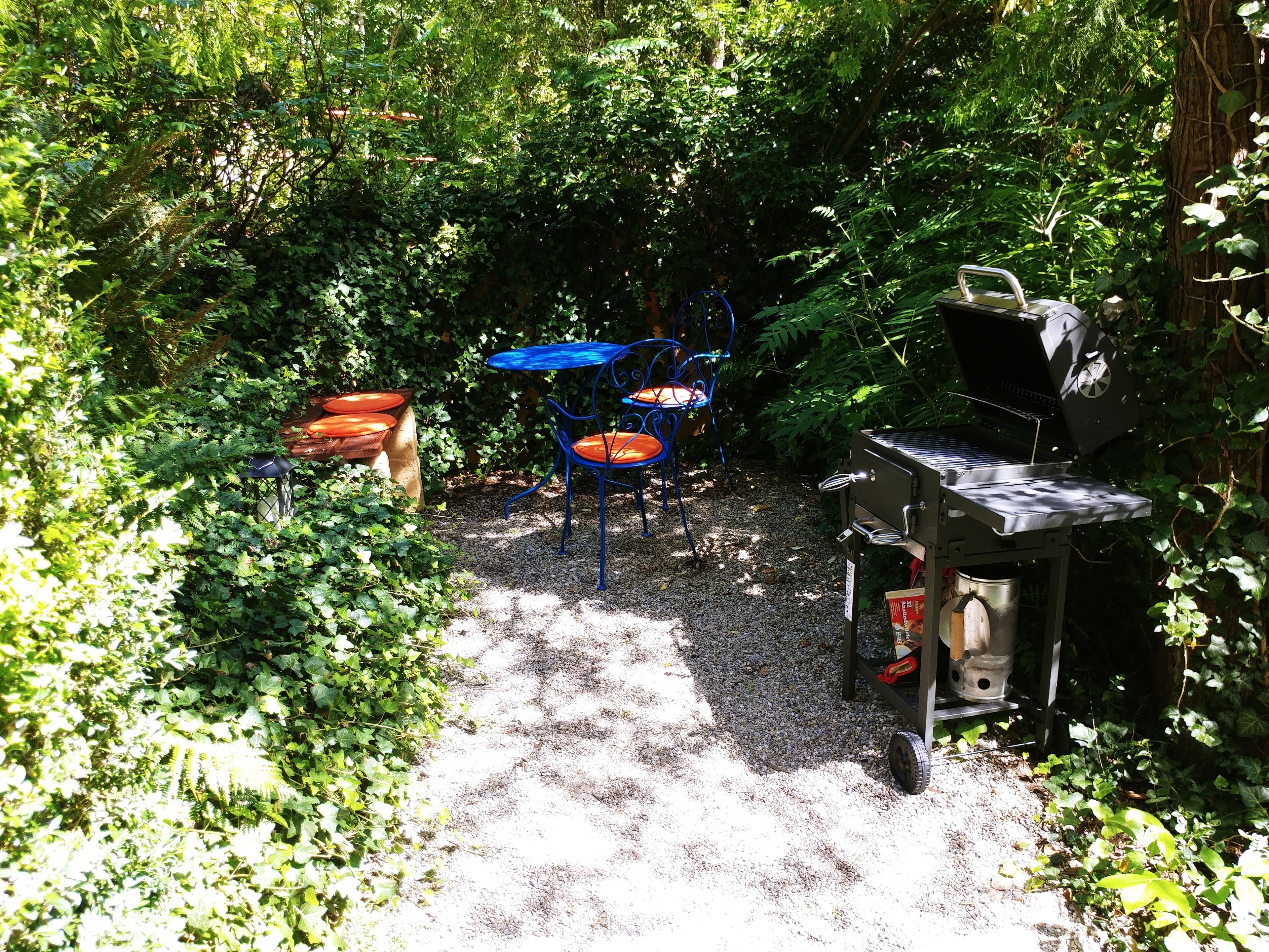 A patio area with a barbecue grill, a table, and two chairs.