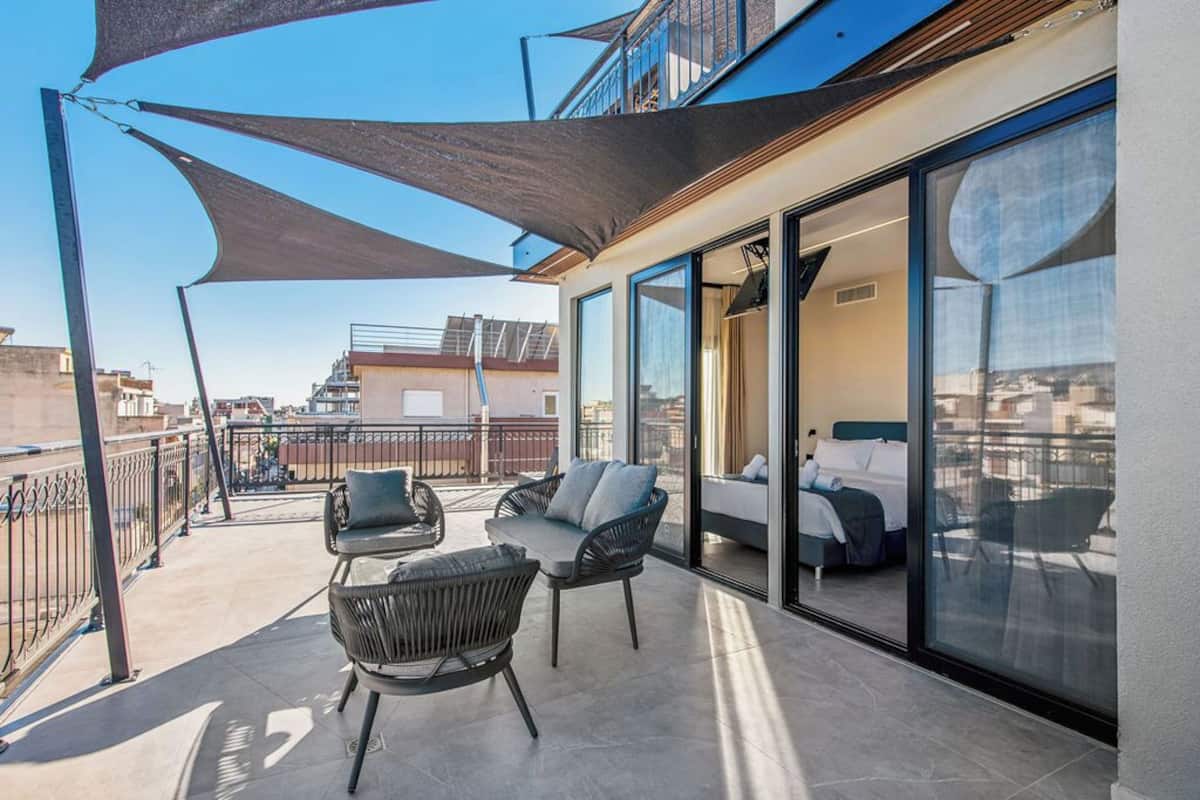 Een balkon met buitenmeubelen en een bed in een moderne kamer.