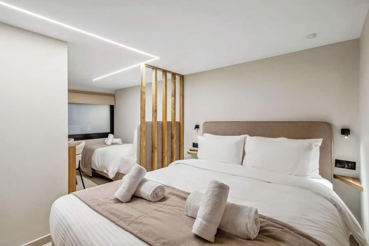 Een moderne hotelkamer met een groot bed, twee nachtkastjes, een houten scheidingswand en een televisie.