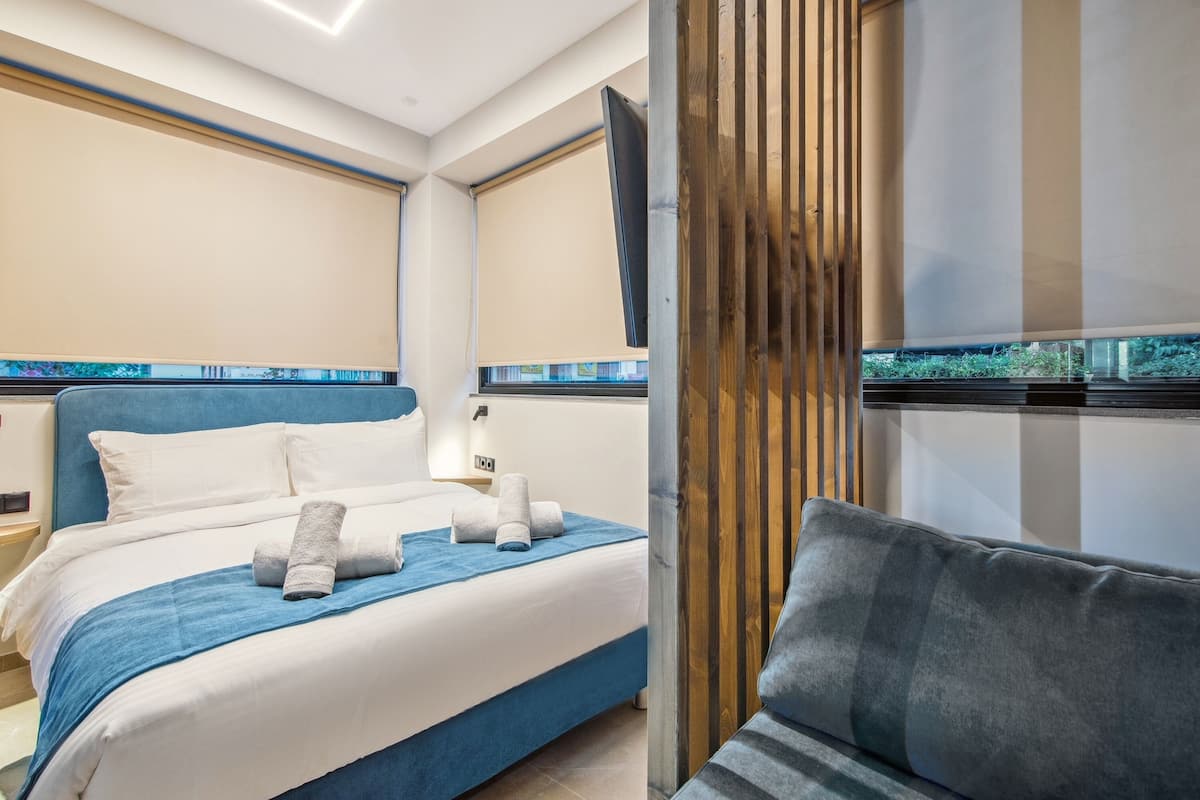 Een moderne hotelkamer met een groot bed, een televisie en uitzicht op groen.