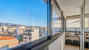 A modern apartment with a balcony, a kitchen area, and a view of a cityscape. - Mc Queen Apartments (Athens)