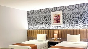A hotel room with two beds, a sofa, and a nightstand with a lamp. - SM Tower Hotel & Convention Center Berau (Tanjung Redeb)