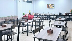 A spacious dining area with multiple tables and chairs, a clock, and a television on the wall. - SM Tower Hotel & Convention Center Berau (Tanjung Redeb)