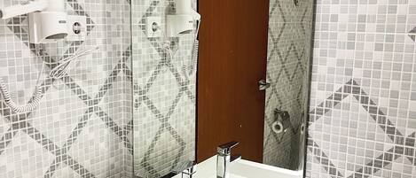 A bathroom with a white sink, a mirror, and a patterned tile wall.
