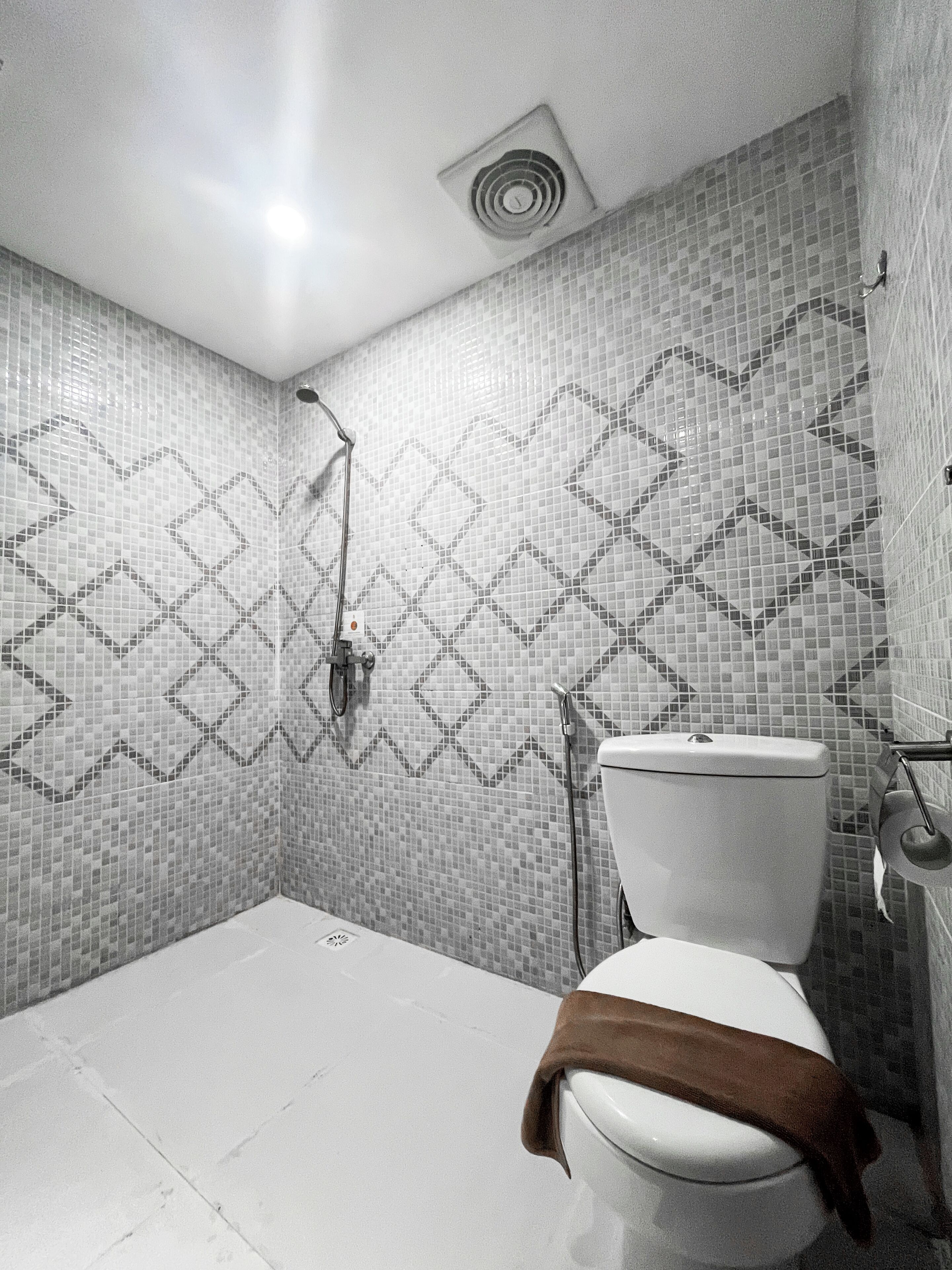 A bathroom with a patterned tile wall, a shower, and a toilet.