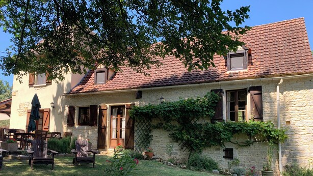 A stone house with a tiled roof, a wooden door, and a window with shutters. There is a potted plant in the front yard. - DOMAINE AUX ETOILES (Salviac)