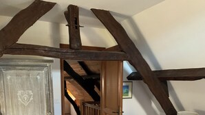A bedroom with exposed wooden beams, a large wardrobe, a bed, and a nightstand with a lamp. - DOMAINE AUX ETOILES (Salviac)