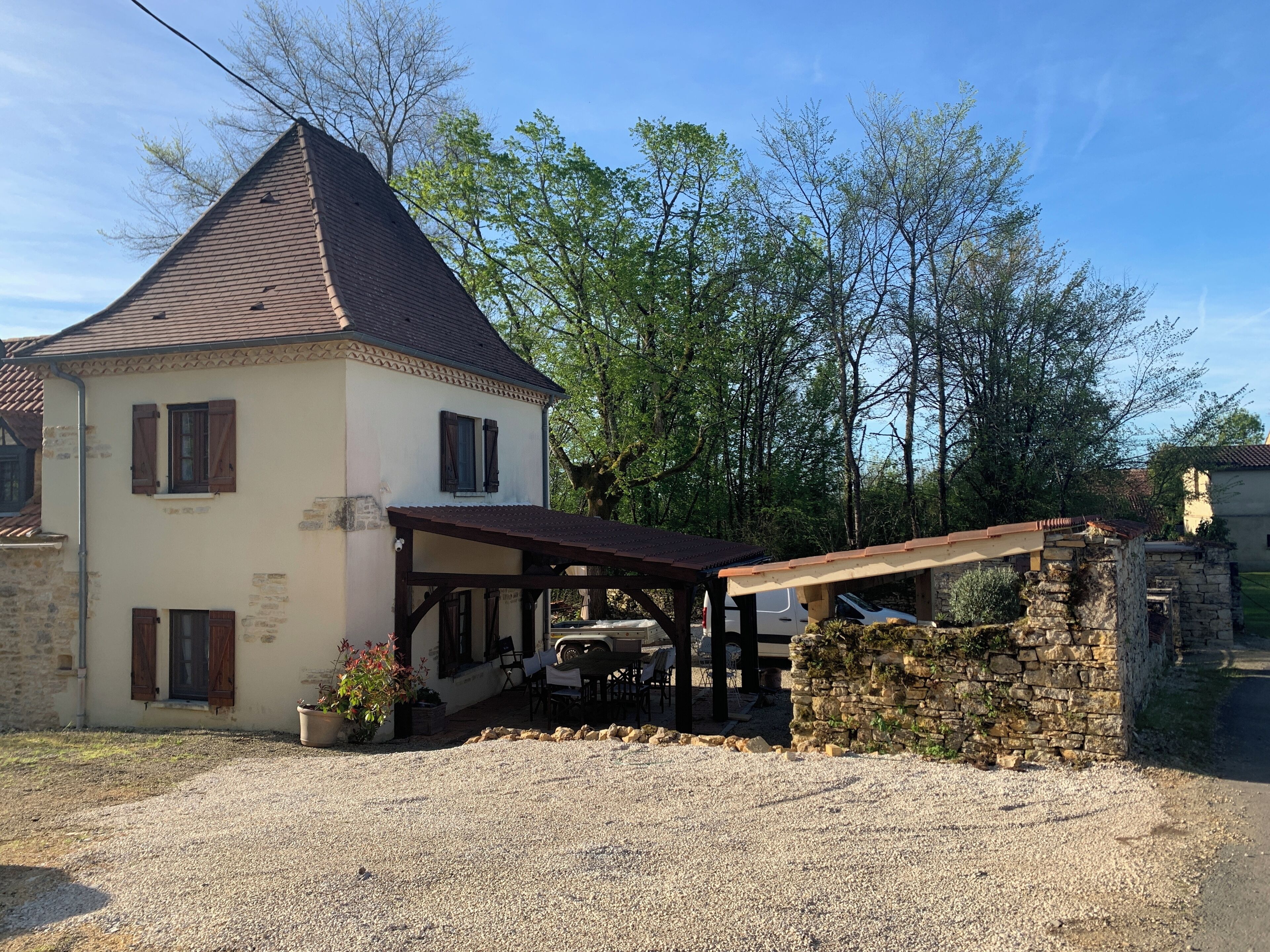 A two-story house with a gravel driveway and a covered patio area.