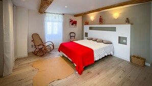 A bedroom with a bed, a rocking chair, a window with curtains, and a wooden ceiling. - Chez mamie (Montdragon)