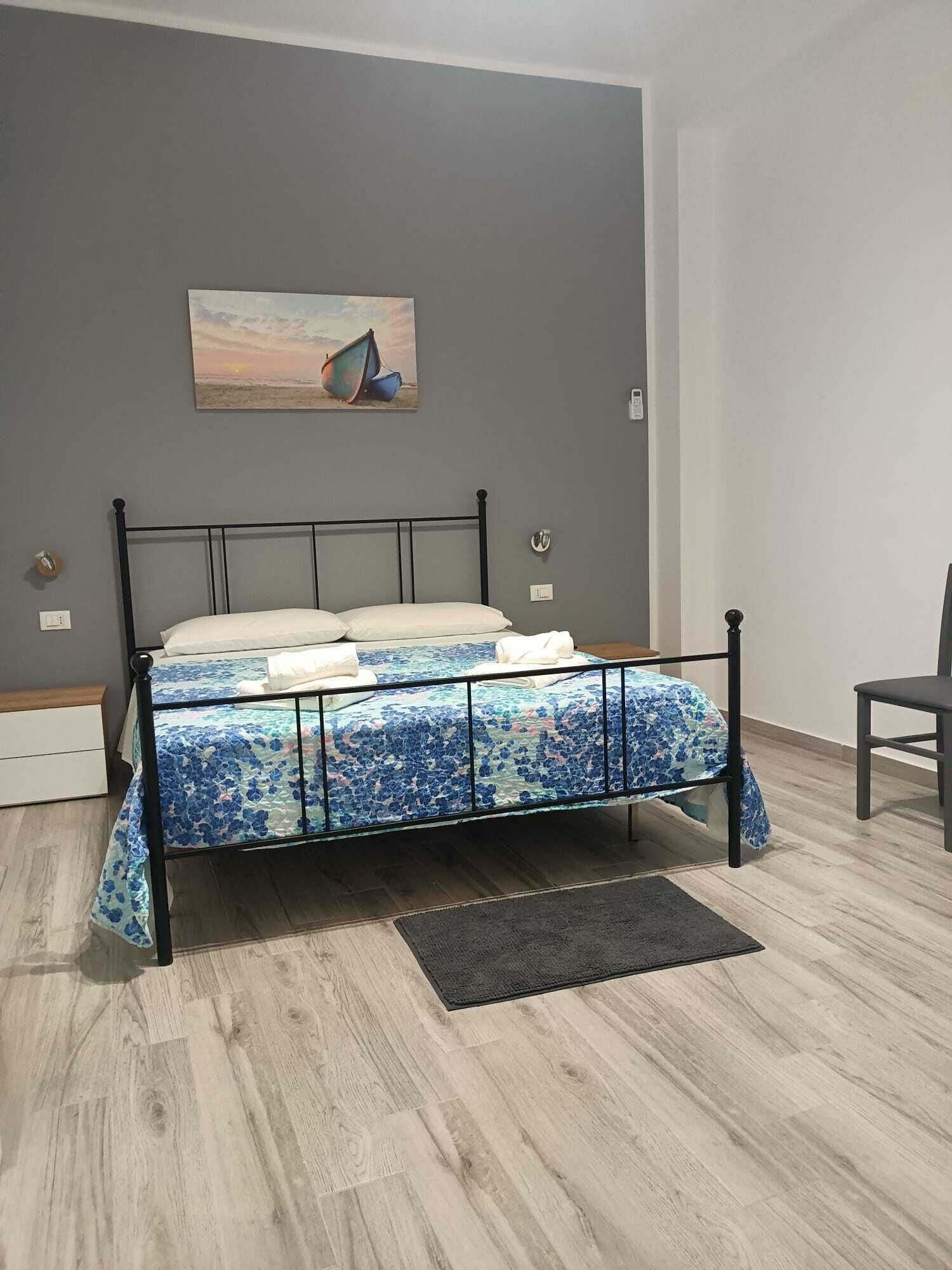 Een slaapkamer met een bed, een schilderij en een stoel.