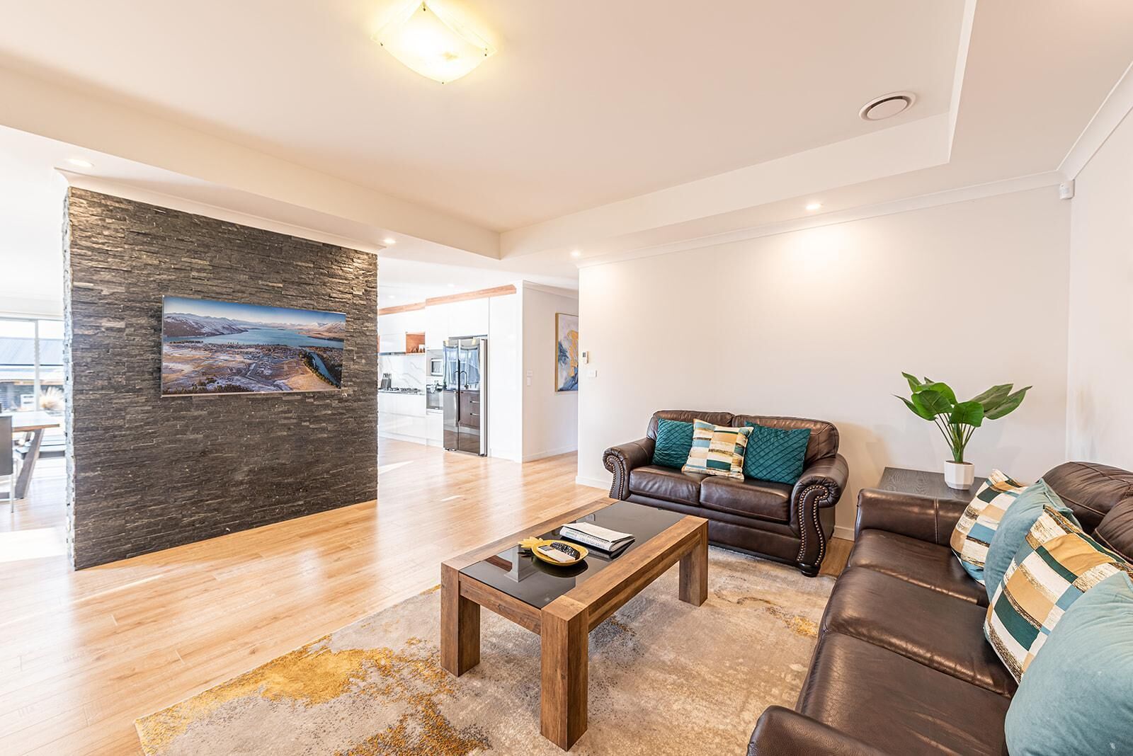 A modern living room with a leather sofa, a coffee table, and a stone accent wall.
