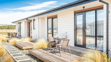 A modern house with a patio area featuring outdoor furniture and a view of the surrounding landscape.
