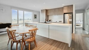 Una cocina moderna con una isla central, sillas de madera y un ventanal con vistas al exterior.