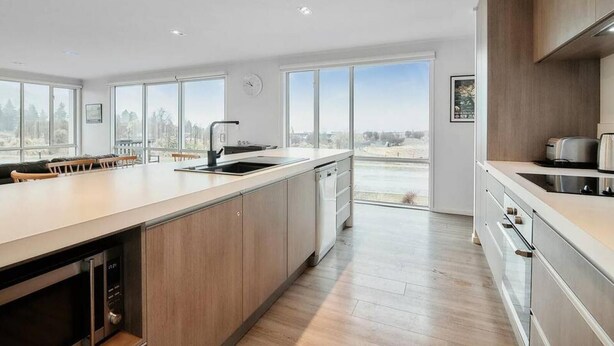 Una cocina moderna con ventanas amplias, lavavajillas y vistas al exterior.