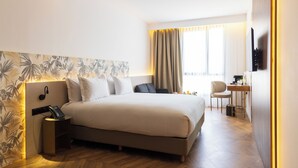 Una habitación de hotel moderna con una cama grande, un escritorio y una silla.