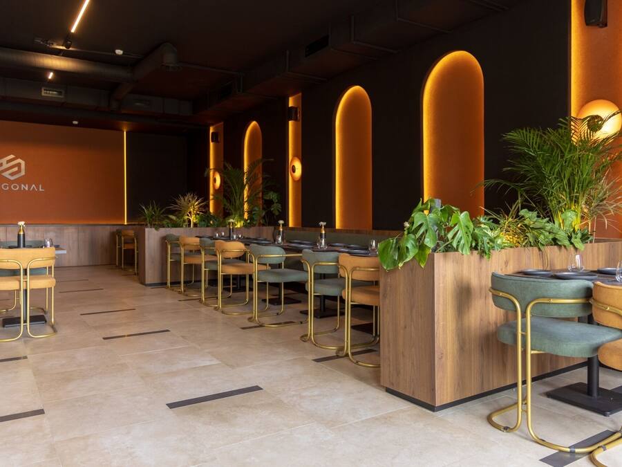 Een modern restaurant met een lange toonbank, verschillende zithoeken en warme verlichting.
