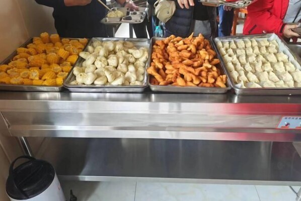 A buffet with four trays of food: corn, dumplings, fried items, and another type of dumpling. - Holiday Inn Wulagai Management Area (East Ujimqin Banner)
