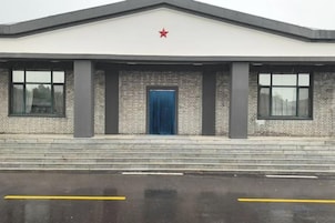 Un edificio con una estrella roja en el techo, una puerta azul y fachada de ladrillo.