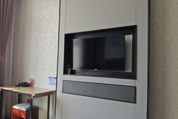A hotel room with a flat-screen TV mounted on the wall, a wooden desk, and a small trash bin. - Holiday Inn Wulagai Management Area (East Ujimqin Banner)