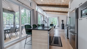 A modern kitchen with a large island, stainless steel appliances, and a view of the outdoors. - Villa Le Frigg | Private Spa • Pet Friendly (Shannon)