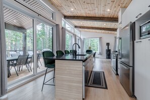 A modern kitchen with a large island, stainless steel appliances, and a view of the outdoors.