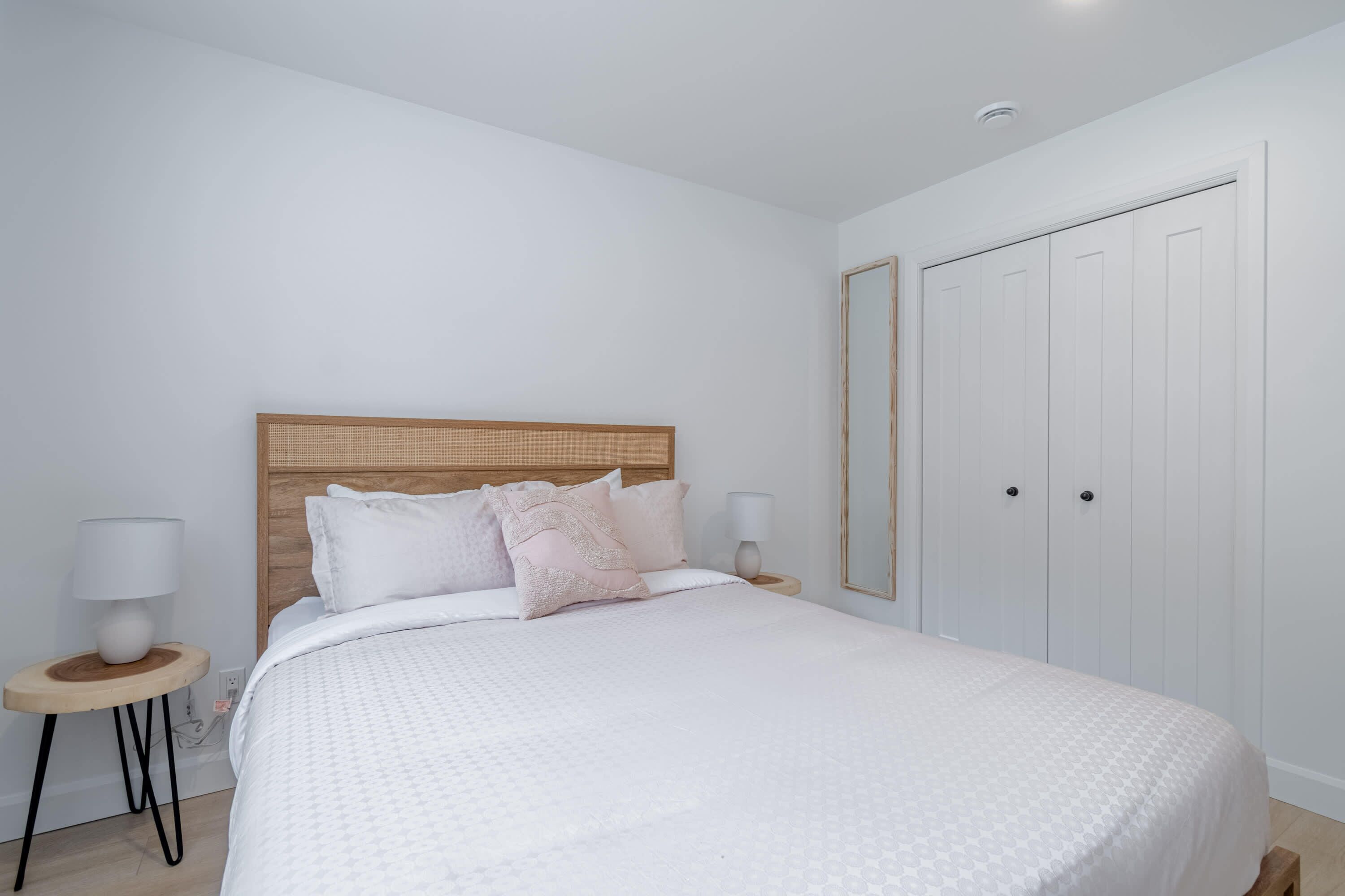 A bedroom with a bed, bedside tables, a wardrobe, and a mirror.