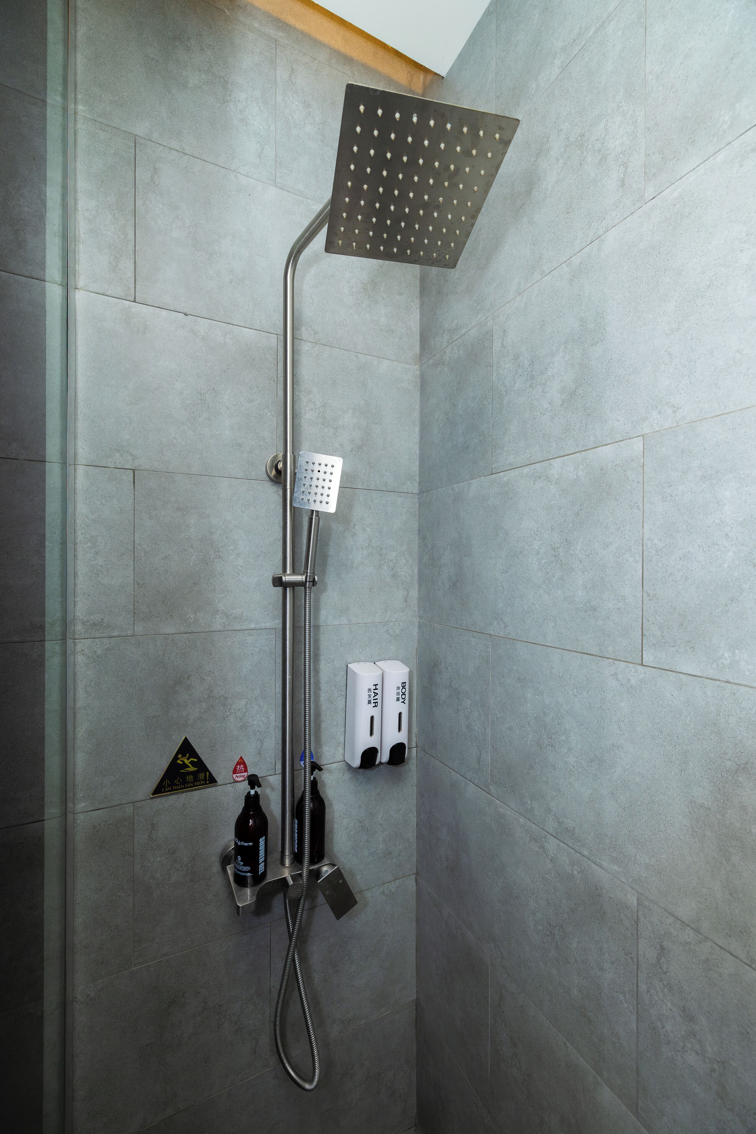 A modern shower with a square showerhead and a handheld shower attachment.
