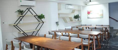 A conference room with multiple tables and chairs, white walls, and air conditioning units.